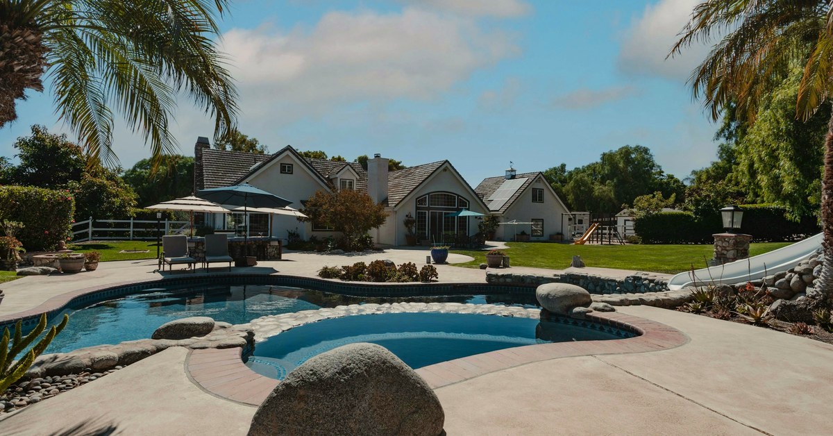 Resurfaced pool deck wrapping a kidney-shaped pool with palm landscaping